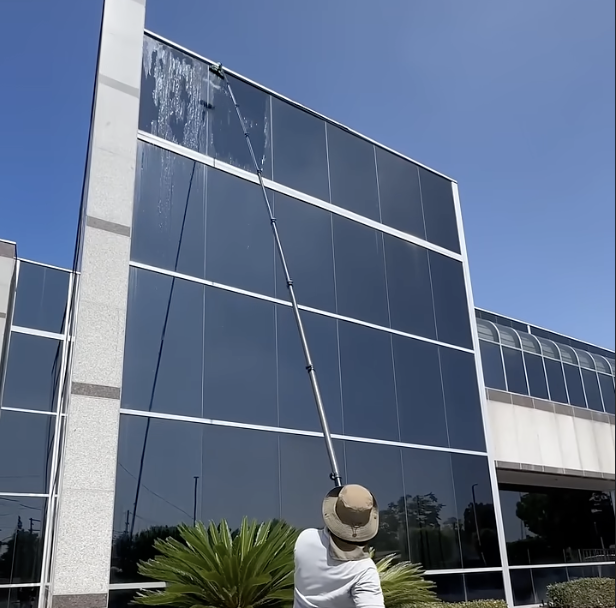 Exit Property Co technician pressure cleaning building windows with a water-fed pole