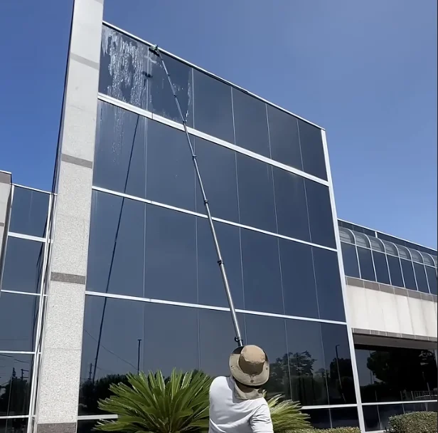 Exit Property Co technician pressure cleaning building windows with a water-fed pole